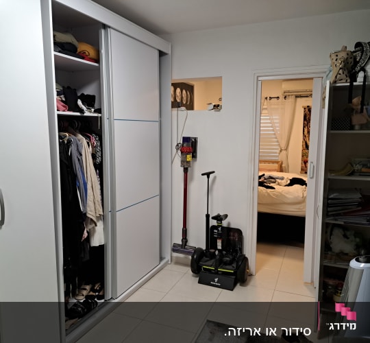 ארון בגדים פתוח עם בגדים תלויים ומדף, מדף עם מסמכים